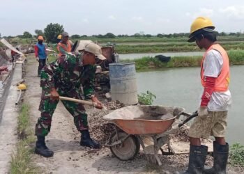 Tak Kenal Libur, Babinsa Koramil Cerme Bantu Warga Bangun Dinding Penahan Jalan