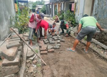 Puasa Ramadan, Babinsa Menganti Tetap Semangat Bantu Warga Pasang Paving Jalan