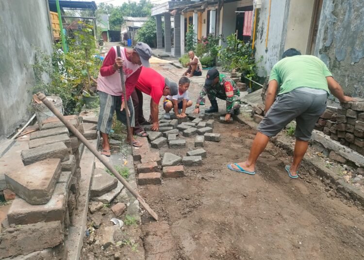 Puasa Ramadan, Babinsa Menganti Tetap Semangat Bantu Warga Pasang Paving Jalan